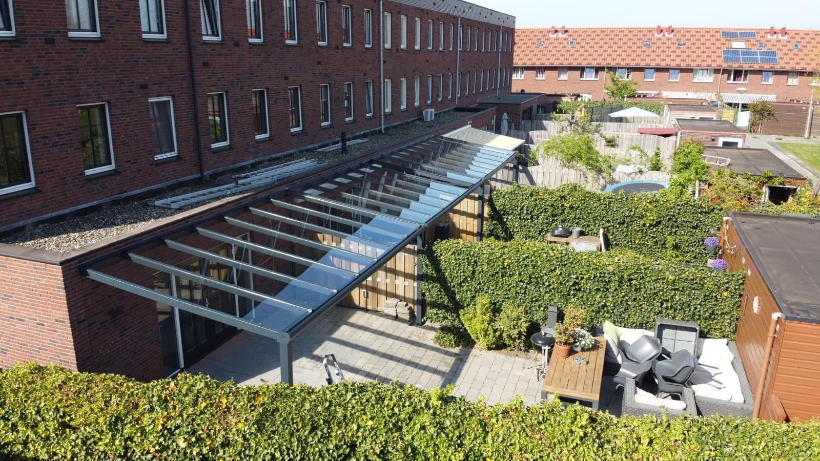 Vue plongeante sur la structure : chevrons anthracite, vitrages et chéneau le long de la façade
